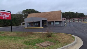 Un Red Roof Inn con estacionamiento y un edificio de techo inclinado.