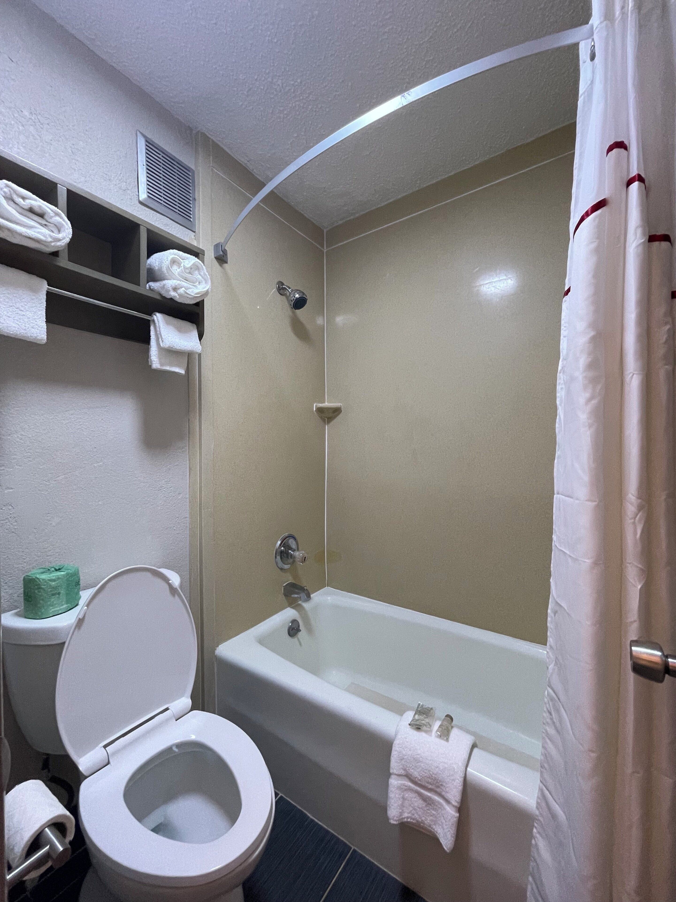 A bathroom with a bathtub, toilet, and shower curtain.