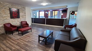 Die Lobby eines Red Roof Inn mit einer Steinsäule, roter Sitzmöbeln und einem großen Fenster.