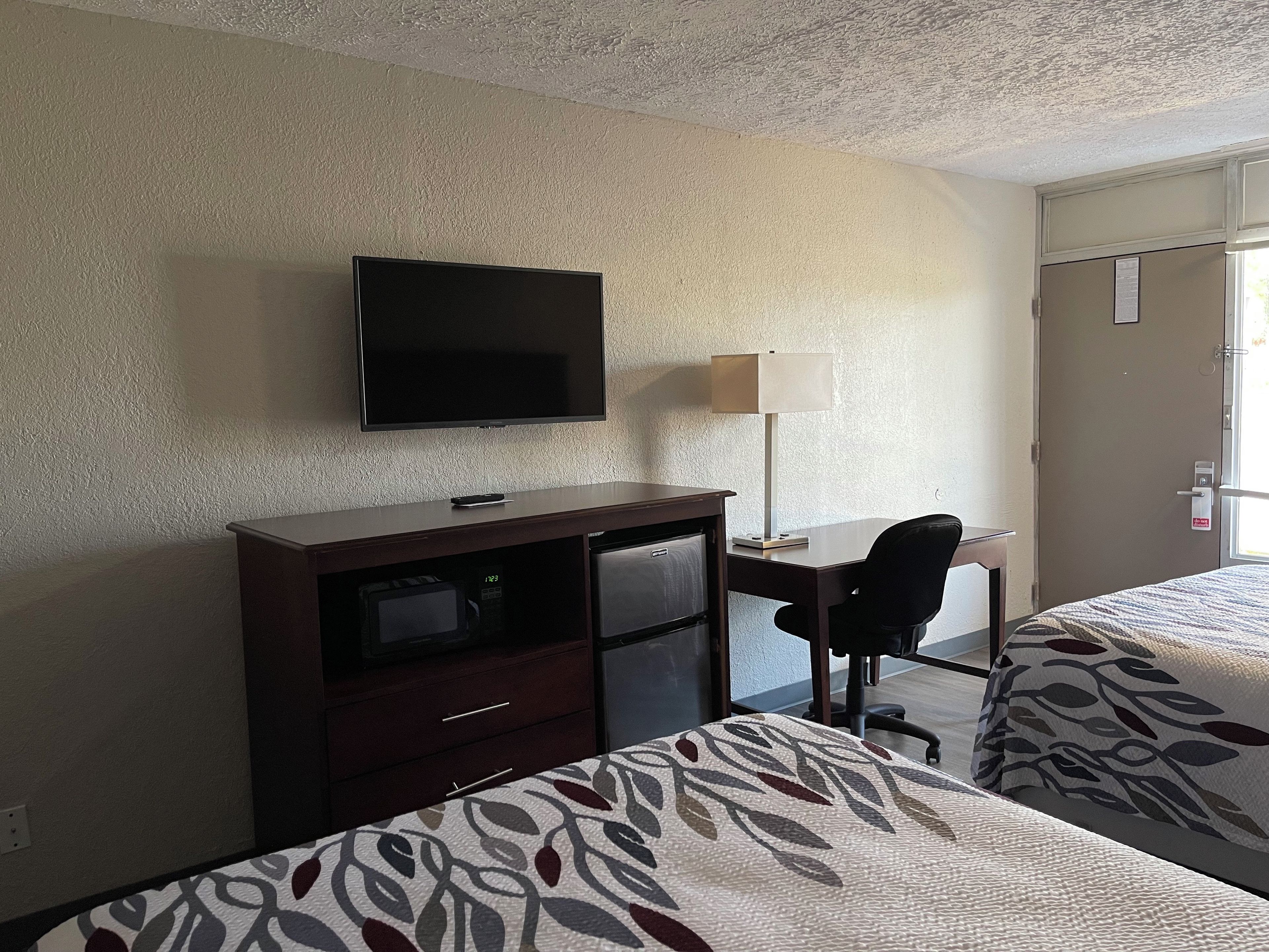 Ein Hotelzimmer mit Bett, Schreibtisch, Fernseher, Lampe und Kleiderschrank.