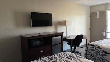 Ein Hotelzimmer mit Bett, Schreibtisch, Fernseher, Lampe und Kleiderschrank.