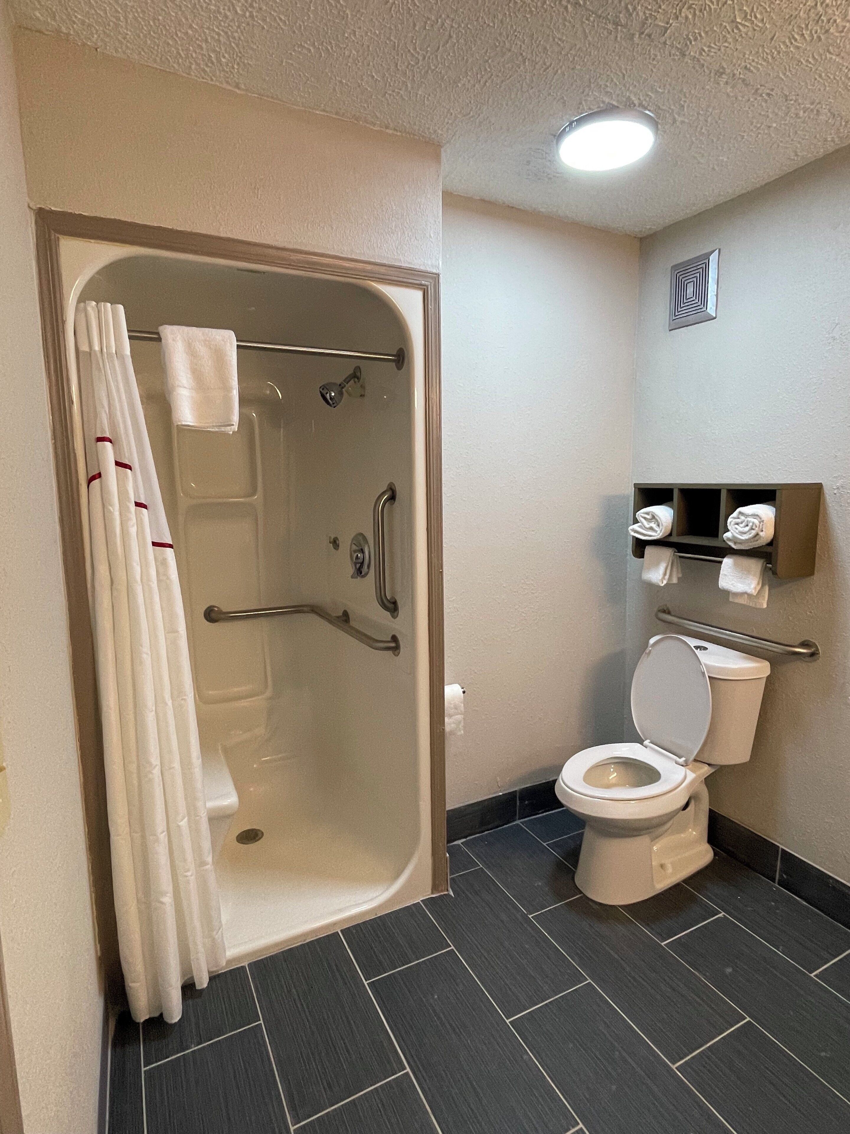 Un baño con bañera, inodoro y barras de apoyo.