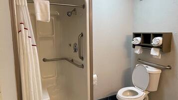 Un baño con bañera, inodoro y barras de apoyo.