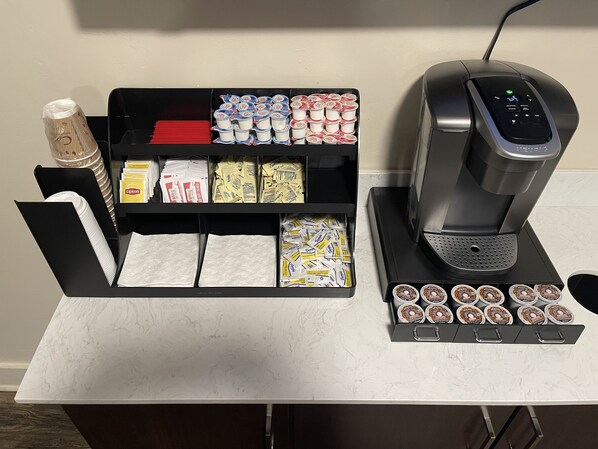 Un espace dédié au café, comprenant une machine à café, un assortiment de dosettes de café et une sélection de serviettes.