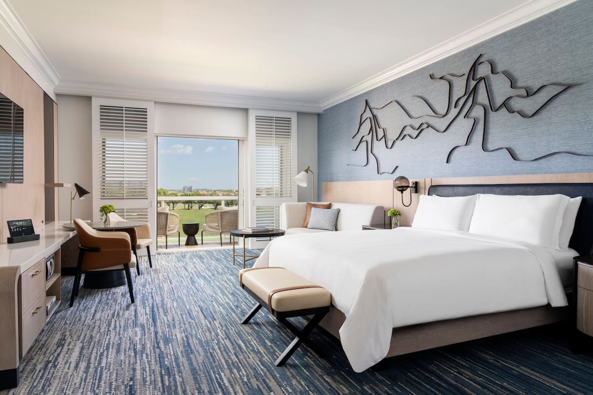 Habitación de hotel con una cama grande, un escritorio, una silla y vistas a la ciudad.