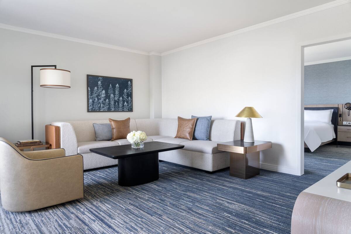 Una habitación de hotel moderna con sofá, mesa de centro, lámpara y cama.