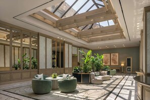 A spacious hotel lobby with a high ceiling, large windows, and a central seating area with sofas and planters. - The Ritz-Carlton Dallas, Las Colinas (Irving)