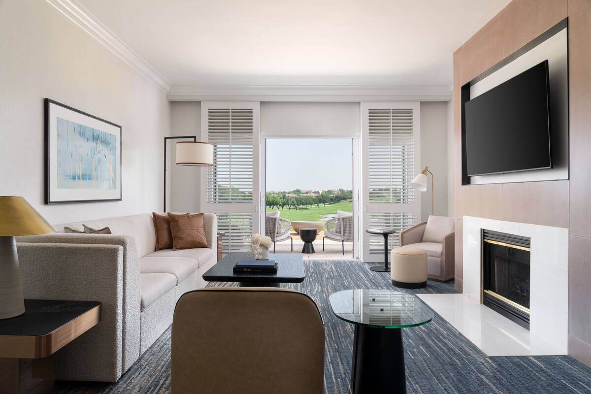 Una sala de estar moderna con un sofá, sillones, una mesa de centro y un televisor montado en la pared.