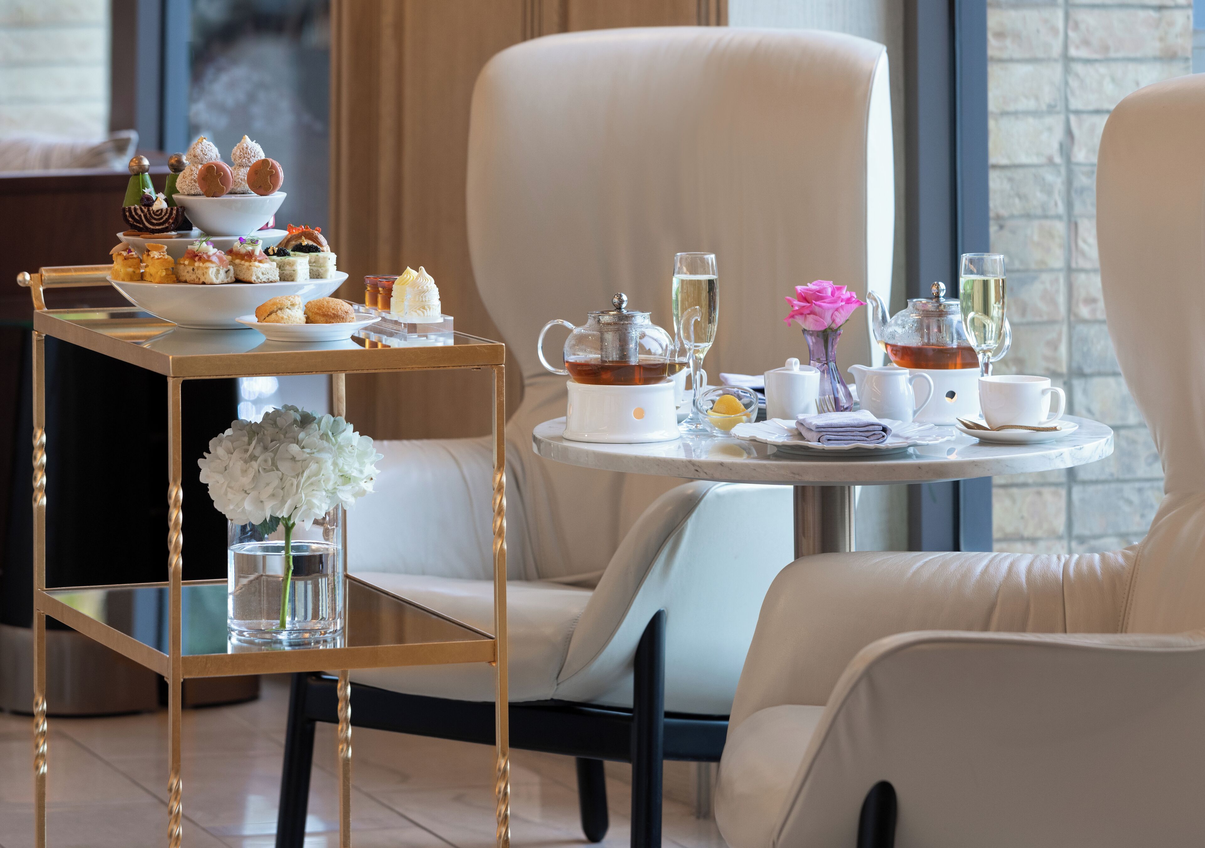 A table set for tea service with a teapot, cups, and a tiered dessert display.
