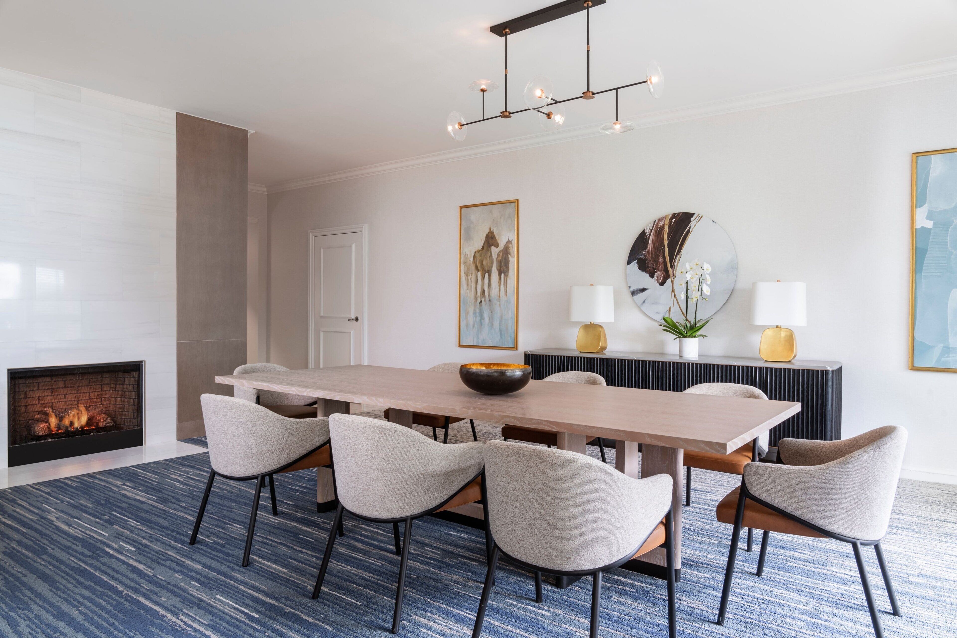 Un comedor moderno con una mesa larga, seis sillas, una chimenea y un candelabro.
