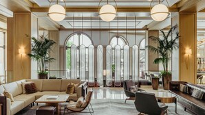Un vestíbulo amplio con diseño moderno, que cuenta con una zona de estar grande, un mostrador de recepción y ventanas amplias con vistas al exterior.