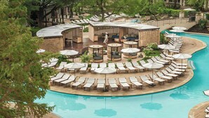 A pool area with lounge chairs and umbrellas, surrounded by wooden structures and greenery. - The Ritz-Carlton Dallas, Las Colinas (Irving)