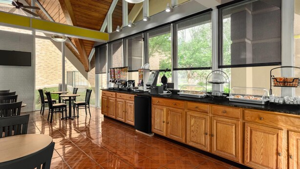 A kitchen with wooden cabinets, a black countertop, and a dining area with chairs and tables.