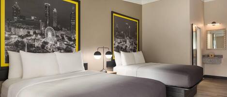 A hotel room with two beds, a large mirror, and two black-and-white cityscape posters on the walls.