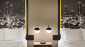 A hotel room with two beds, a nightstand, and a wall mural of a cityscape.