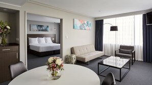 Et hotelværelse med en seng, en sofa, et sofabord og et spisebord.