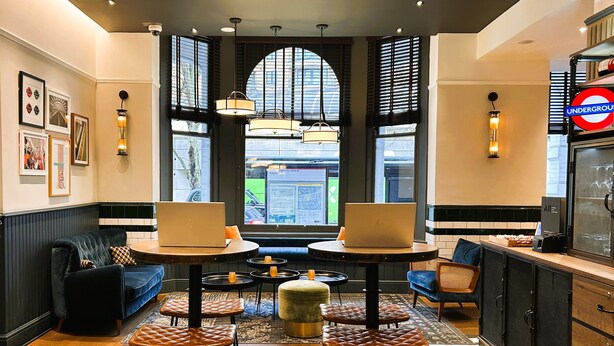 A modern interior with a seating area featuring tables and chairs, a sofa, and a coffee machine. - ibis Styles London Gloucester Road (London)