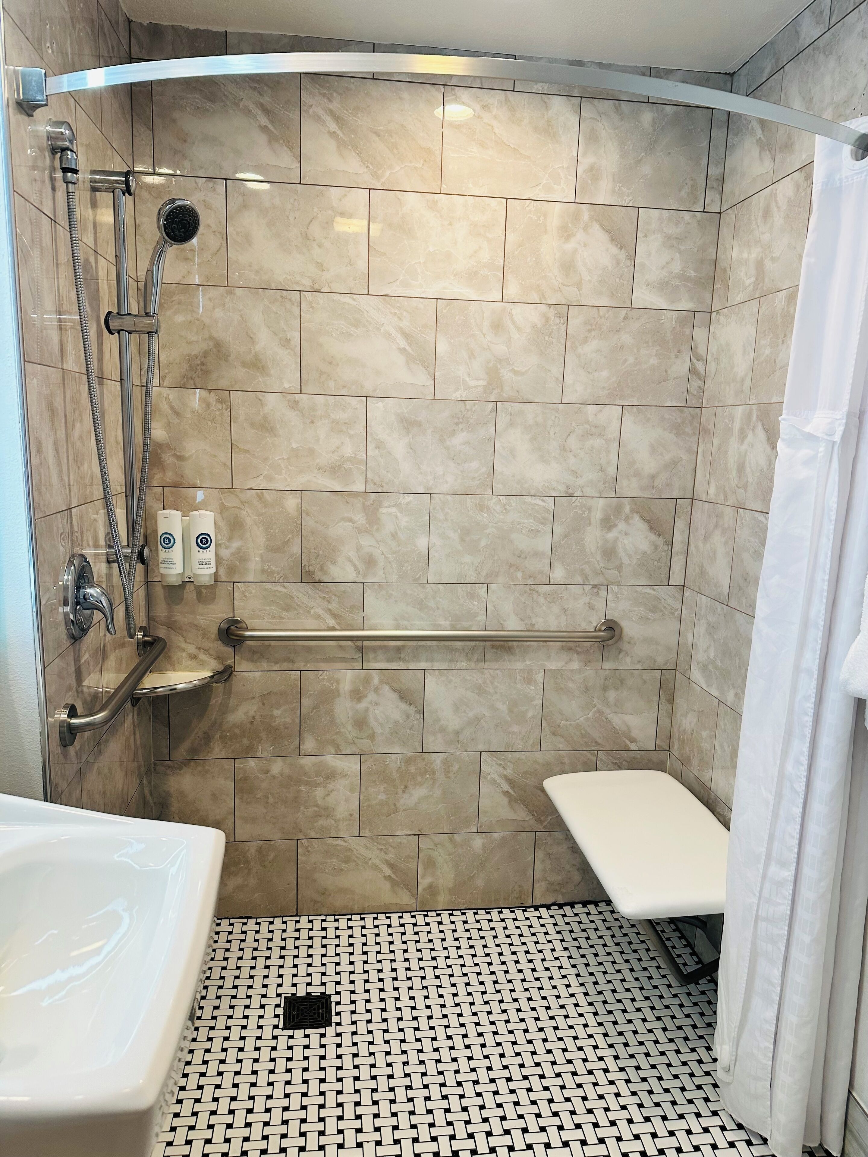 Une salle de bain moderne équipée d’une douche, de barres d’appui et d’une baignoire.