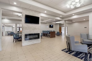 A spacious lobby with a fireplace, seating area, and a television screen.