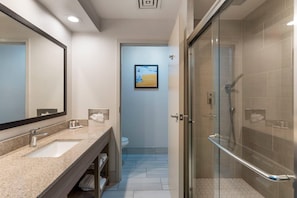 A modern bathroom with a sink, mirror, toilet, and glass shower enclosure.