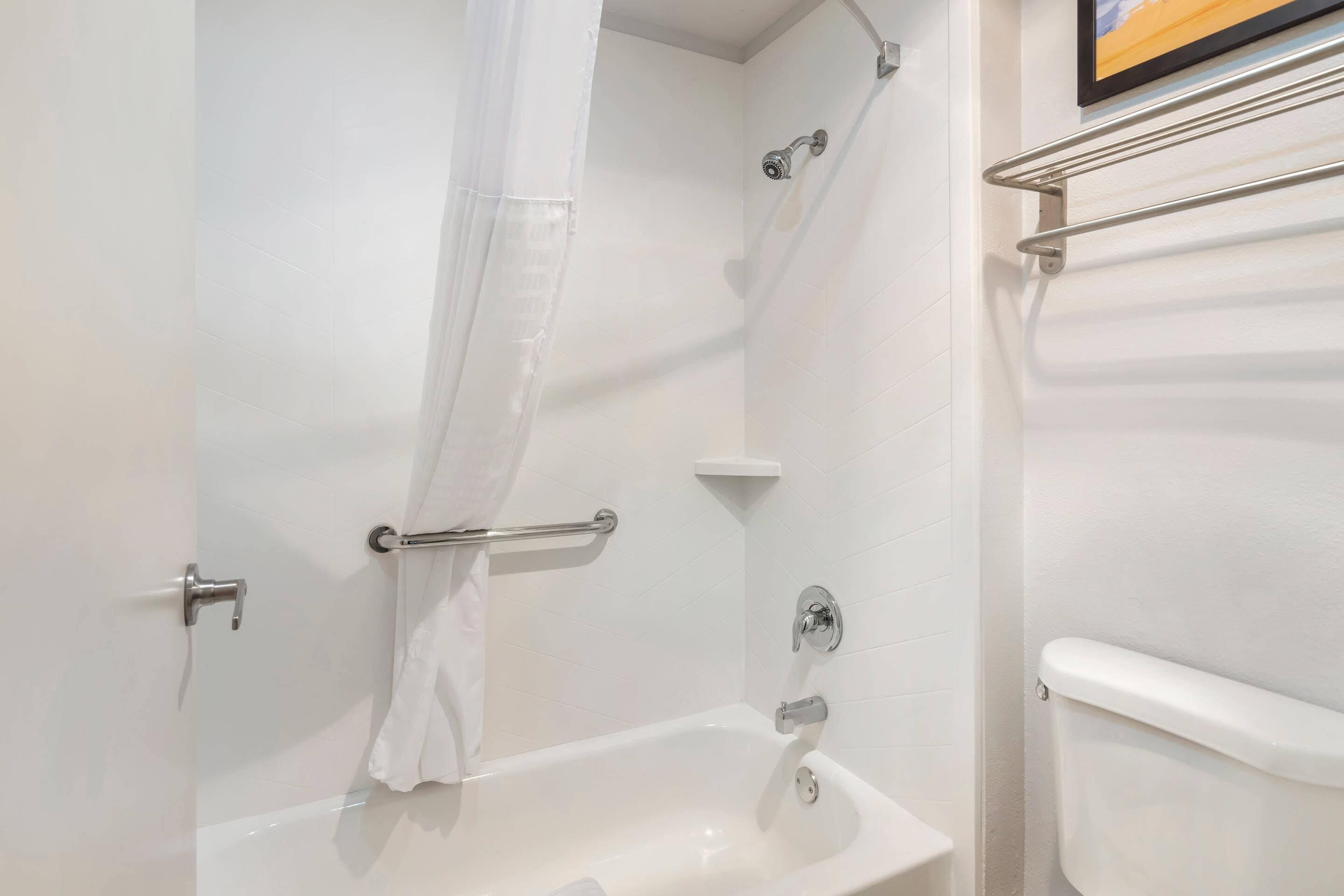 Un baño con bañera, ducha, inodoro y un perchero para toallas.