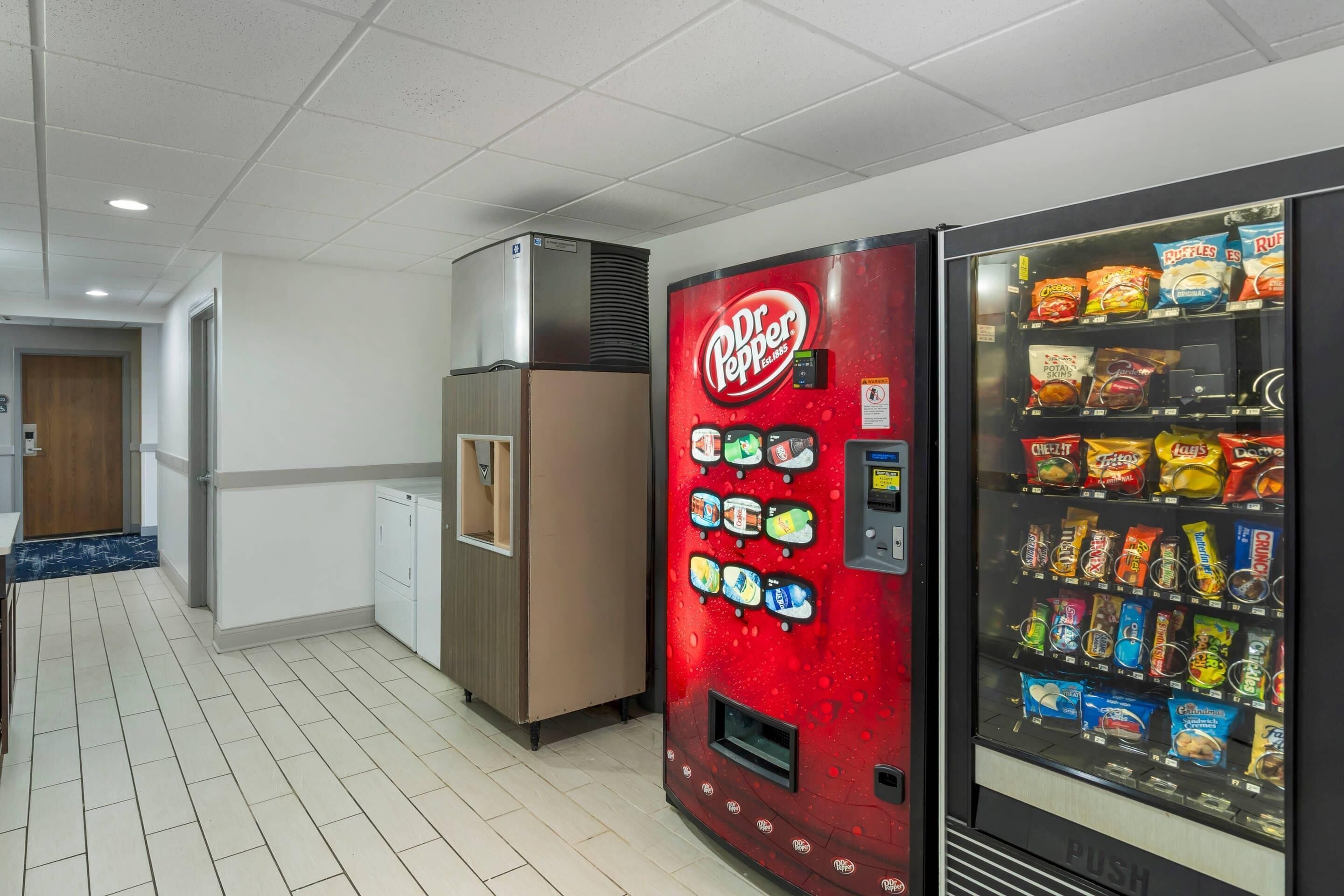 A Dr. Pepper vending machine and a snack vending machine in a hotel corridor.