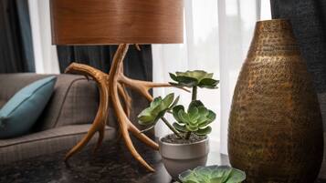 Una sala de estar con una lámpara de pie moderna, una planta suculenta en maceta y un jarrón decorativo.