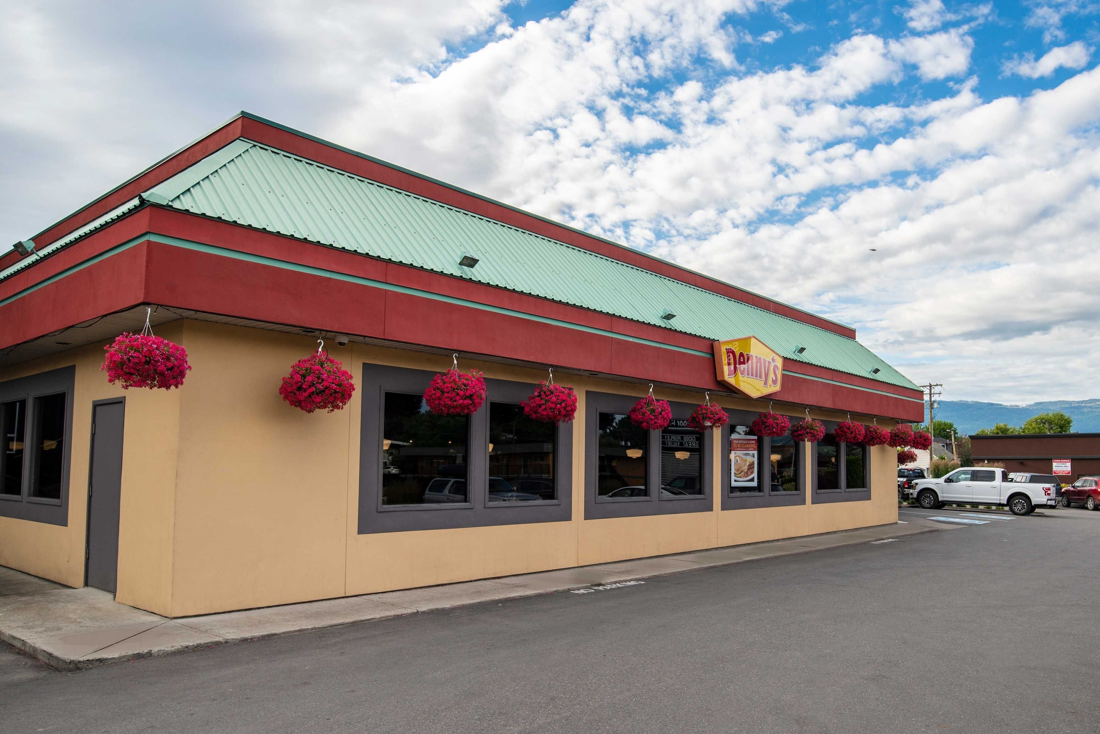 A restaurant with a green roof, red trim, and hanging flower baskets.