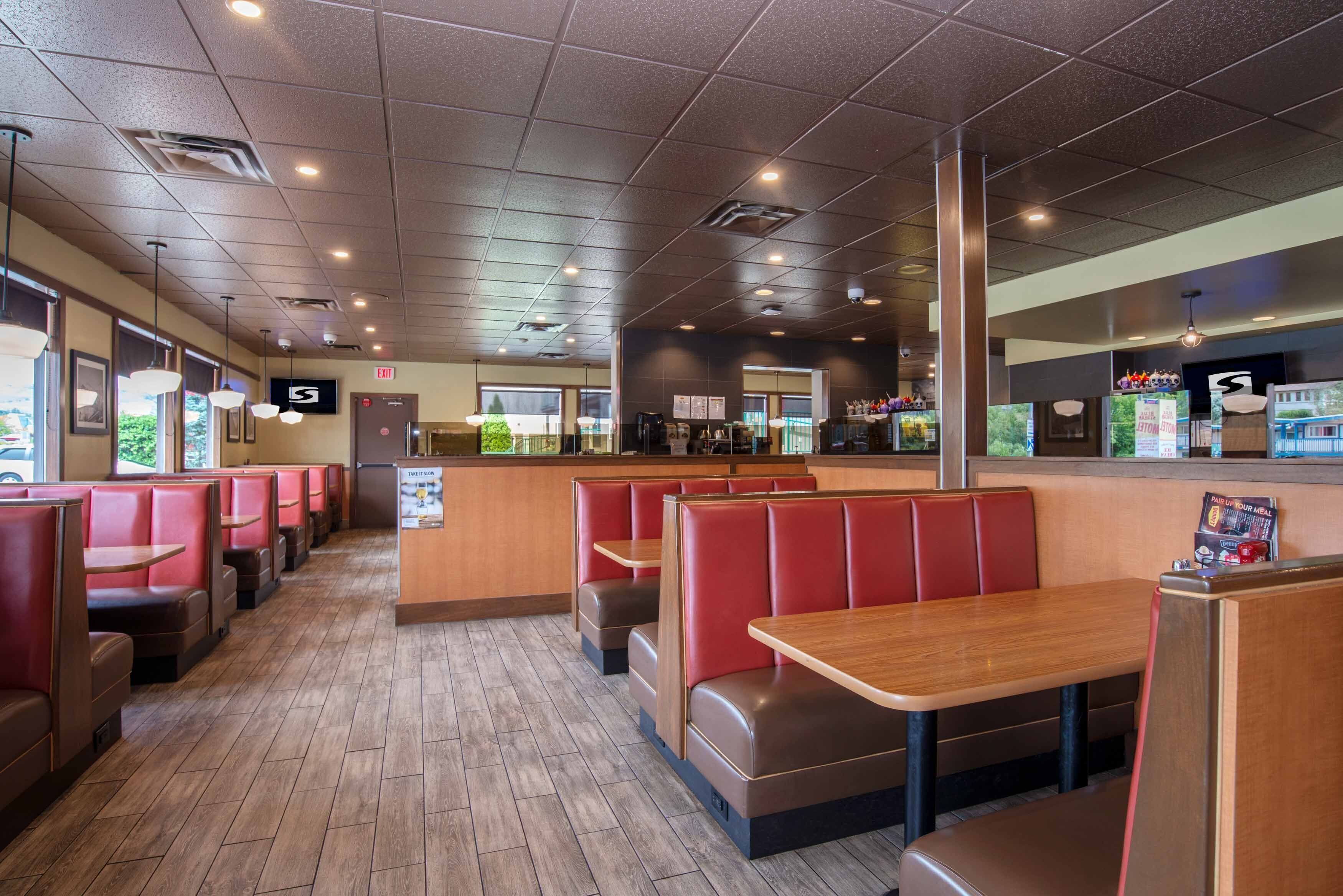 A restaurant interior with booths and tables, a counter, and a view of the outside.