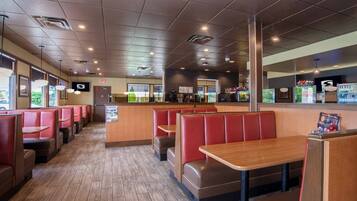 A restaurant interior with booths and tables, a counter, and a view of the outside.