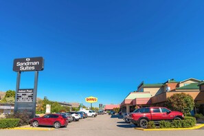 A hotel entrance with a sign for Sandman Suites and a large Denny's sign in the background. - Sandman Hotel Vernon (Vernon)