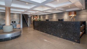 Un vestíbulo moderno con una recepción central, una escalera y una zona de estar.