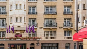 A multi-story hotel with balconies, a visible entrance with a sign, and a flower box with red flowers. - Mercure Paris Opéra Faubourg Montmartre (Paris)