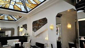 A modern interior with a high ceiling, geometric patterned floor, and contemporary furniture. - Mercure Paris Opéra Faubourg Montmartre (Paris)