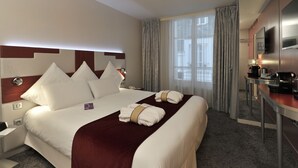 A hotel room with a large bed, a desk with a coffee maker, and a TV on the wall. - Mercure Paris Opéra Faubourg Montmartre (Paris)