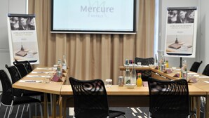 A conference room with a long table, black mesh chairs, and a screen displaying 'Mercure Hotels'. - Mercure Paris Opéra Faubourg Montmartre (Paris)