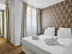 A hotel room with a large bed, white bedding, a patterned wallpaper, and a view of the outdoors through sheer curtains. - Mercure Paris Opéra Faubourg Montmartre (Paris)