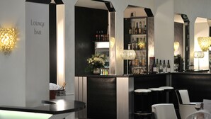 A bar area with a counter, bar stools, and a mirrored wall reflecting the bar's interior. - Mercure Paris Opéra Faubourg Montmartre (Paris)
