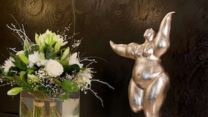 A vase with flowers and a silver statue on a table. - Mercure Paris Opéra Faubourg Montmartre (Paris)