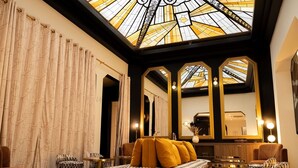 A luxurious room with a large sofa, matching ottomans, a mirror, and a ceiling with stained glass. - Mercure Paris Opéra Faubourg Montmartre (Paris)
