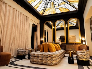A luxurious room with a large sofa, matching ottomans, a mirror, and a ceiling with stained glass. - Mercure Paris Opéra Faubourg Montmartre (Paris)