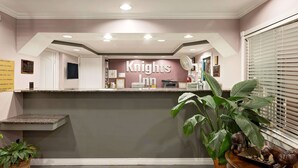 Un área de recepción con mostrador, un cartel que dice "Knights Inn" y una planta grande en maceta.