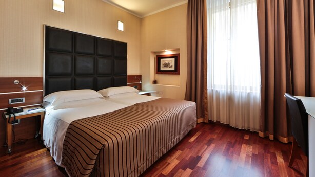 A hotel room with a large bed, a desk, and a nightstand. - Best Western Hotel Madison (Milan)