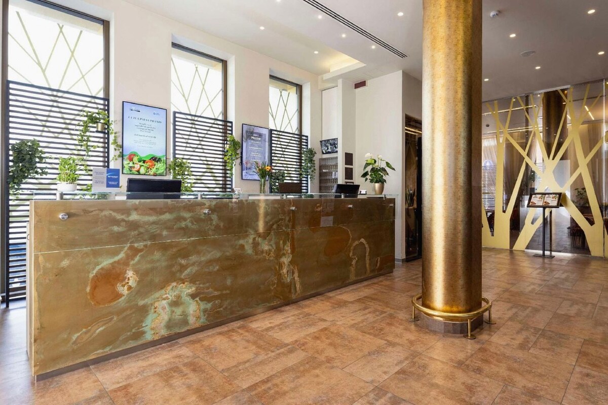 A reception area with a marble counter, potted plants, and a large pillar.