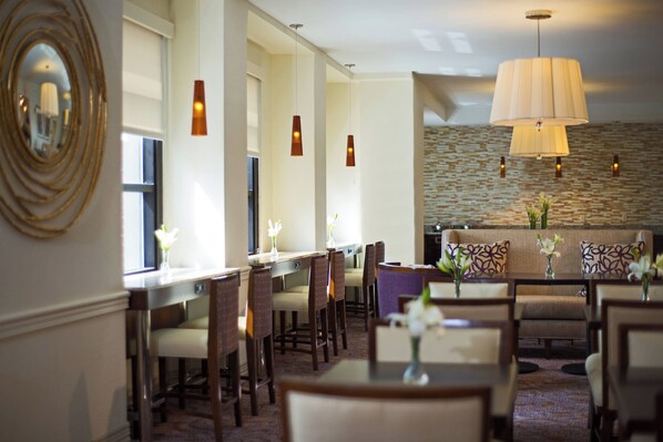 A hotel dining area with long tables, chairs, and hanging pendant lights. - Peoria Marriott Pere Marquette (Peoria)
