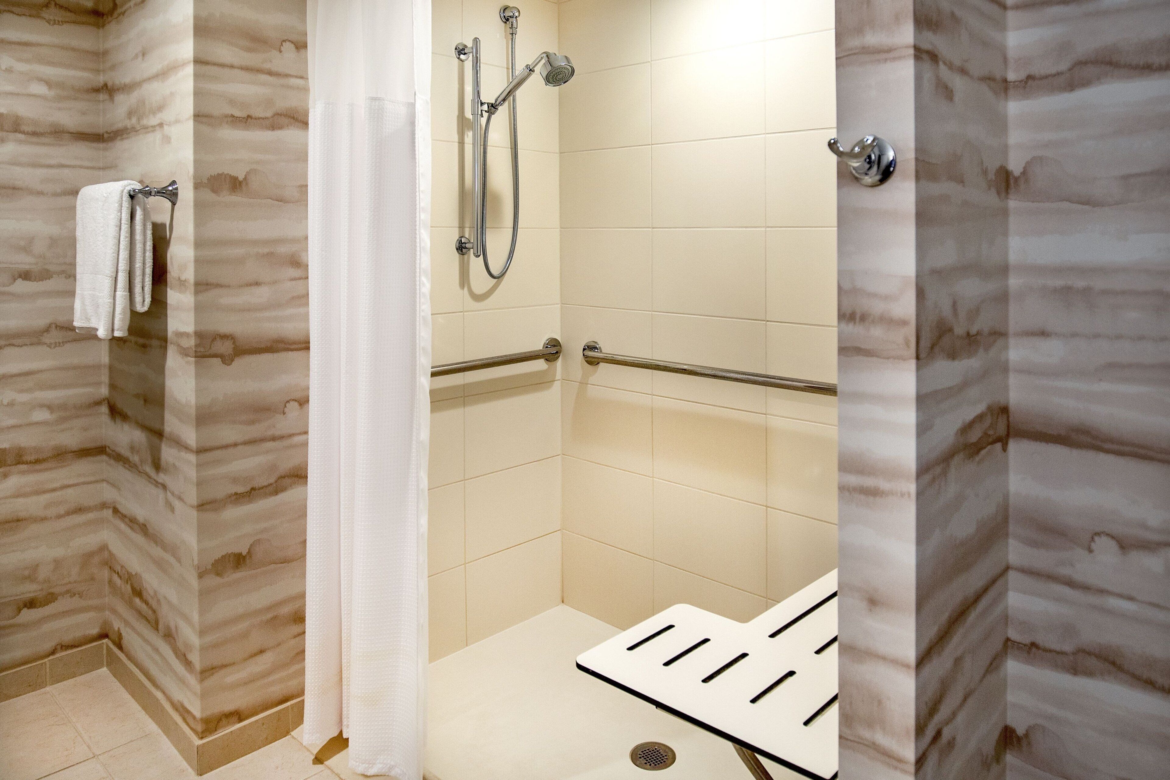 Un espace douche moderne doté d’une porte en verre, d’un porte-serviettes et d’un pommeau de douche.