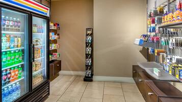 A hotel lobby with a refrigerated beverage display, a life insurance advertisement, and a variety of toiletries on shelves.