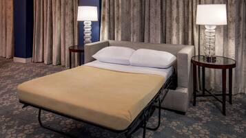 A hotel room with a bed, two bedside tables, a lamp, and a curtain backdrop.