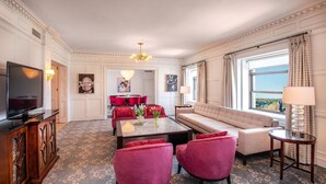 Un salon spacieux avec un canapé, des fauteuils rouges, une table basse et un téléviseur.