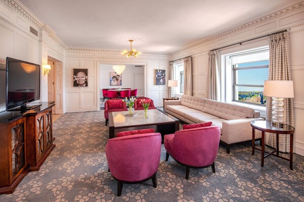 A spacious living room with a sofa, red chairs, a coffee table, and a television. - Peoria Marriott Pere Marquette (Peoria)
